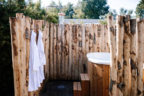 Eine Außendusche und ein Holzbadezuber im Tiny Wellness Cabin im Holiday Park De IJsvogel, Niederlande.