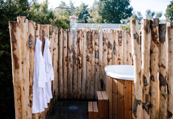 Udendørs bruser og badekar omgivet af trævægge ved Tiny Wellness Cabin i Holiday Park De IJsvogel.