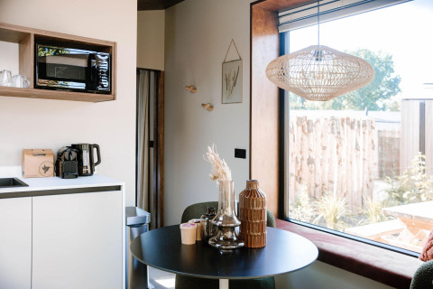 Tiny Wellness Cabin at Holiday Park De IJsvogel with modern kitchenette, table, and large window, Netherlands.