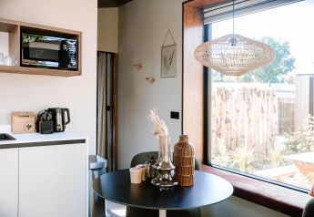 Tiny Wellness Cabin avec coin cuisine moderne, table et grande fenêtre au Holiday Park De IJsvogel, Pays-Bas.