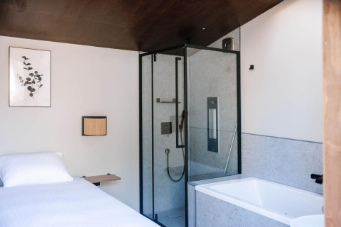 Modernes Tiny Wellness Cabin mit Bett, Dusche und Badewanne im Holiday Park De IJsvogel, Niederlande.