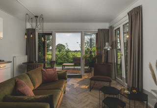 Sala de estar elegante en River Lodge Wellness en Holiday Park Mölke, Países Bajos, con vista a la naturaleza.