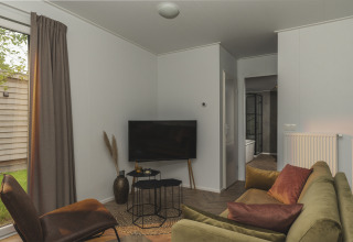 Stue i River Lodge Wellness ved Holiday Park Mölke, Holland, med grøn sofa, brun stol og tv.