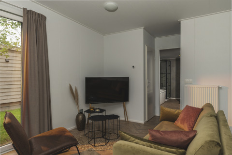 Living room at River Lodge Wellness, Holiday Park Mölke, Netherlands, with green sofa and television.