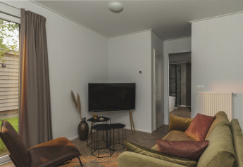 Wohnzimmer im River Lodge Wellness im Holiday Park Mölke, Niederlande, mit grünem Sofa und TV.