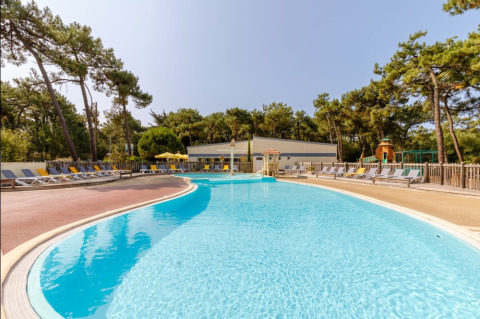 Outdoor swimming pool with sun loungers and trees at Camping Le Bois de la Gachère holiday park, Pays de la Loire, France.