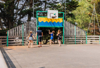 Family enjoys a game of basketball outdoors at Camping Le Bois de la Gachère holiday park in France.