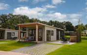 Panorama Lodge med hot tub i Vakantiepark Hölte, Holland, lille hus omgivet af grønt område.