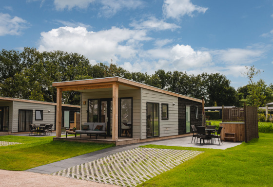 Panorama Lodge med hot tub i Vakantiepark Hölte, Holland, lille hus omgivet af grønt område.