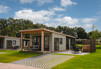 Panorama Lodge med hot tub i Vakantiepark Hölte, Holland, lille hus omgivet af grønt område.