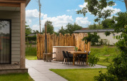 Cozy terrace at Panorama Lodge tiny house with hot tub and wooden fence at Vakantiepark Hölte, Netherlands.