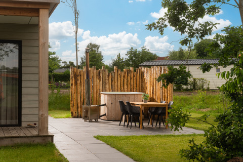 Hyggelig terrasse ved tiny house Panorama Lodge med spabad og træhegn i Vakantiepark Hölte, Holland.