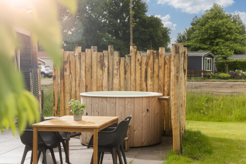 Whirlpool und rustikale Holzabtrennung neben einem Tisch an der Panorama Lodge im Vakantiepark Hölter, Niederlande.