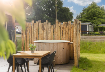 Buiten hot tub met houten schutting en tafel bij de Panorama Lodge in Vakantiepark Hölte, Nederland.