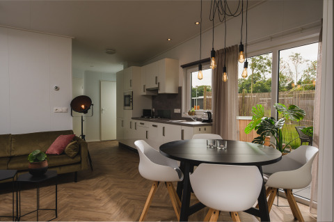 Moderne, hyggelig Panorama Lodge med spisebord, køkken og store vinduer i Vakantiepark Hölte, Holland.