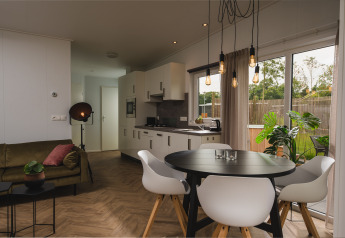 Moderne Panorama Lodge met keuken en eethoek bij Vakantiepark Hölte in Nederland, zicht op tuin.