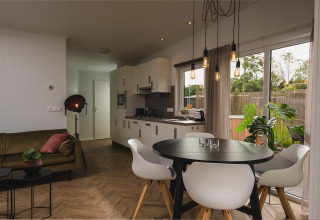 Moderne, hyggelig Panorama Lodge med spisebord, køkken og store vinduer i Vakantiepark Hölte, Holland.