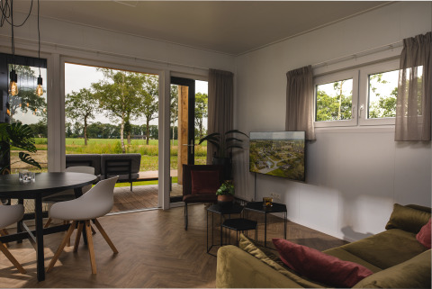 Sala moderna en la Panorama Lodge de Vakantiepark Hölte, Países Bajos, con vistas al campo verde.