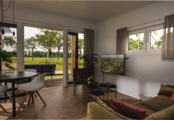 Moderne leefruimte in Panorama Lodge op Vakantiepark Hölte in Nederland, met uitzicht op groen veld.