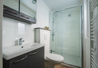 Bagno moderno e compatto al Panorama Lodge di Vakantiepark Hölte, Paesi Bassi, con doccia e lavandino.