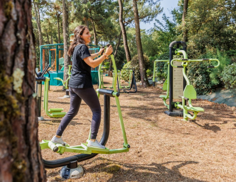 Donna che si allena con attrezzi fitness all’aperto in un parco vacanze boscoso a Pays de la Loire, Francia.