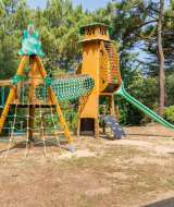 Legeplads med klatrestativ, rutsjebane og træbænke på Camping Le Bois de la Gachère i Pays de la Loire.