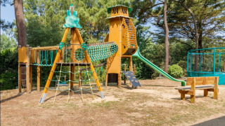 Legeplads med klatrestativ, rutsjebane og træbænke på Camping Le Bois de la Gachère i Pays de la Loire.