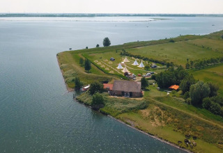 Vista aerea della tenda Safari Cozy presso TinyParks Cast Away nei Paesi Bassi, tra lago e campi verdi.