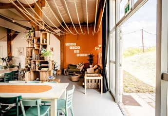 Interno di una tenda safari con zona relax accogliente, tavolo da pranzo e luce naturale nei Paesi Bassi.