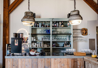 Rustikale Kaffeebar mit Holztresen und Regalen im Safari-Zelt bei TinyParks Cast Away, Niederlande.