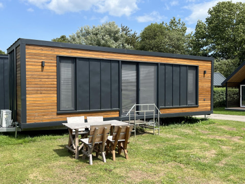Moderna casa pequeña en el parque recreativo y marina Rhederlaagse Meren en Países Bajos con mesa exterior.