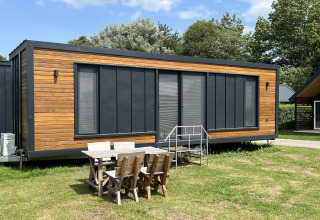 Moderne tiny house lodge aan recreatiepark en jachthaven Rhederlaagse Meren in Nederland met terrasmeubilair.