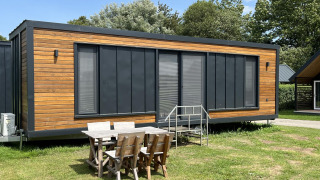 Modernes Tiny House im Erholungspark und Jachthafen Rhederlaagse Meren in den Niederlanden mit Sitzgruppe.