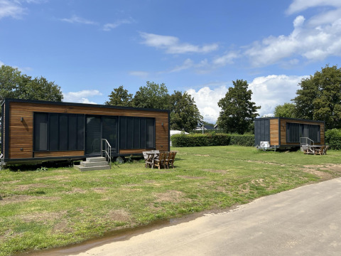 Zwei moderne Tiny Houses auf einer grünen Wiese im Erholungspark und Marina Rhederlaagse Meren, Niederlande.