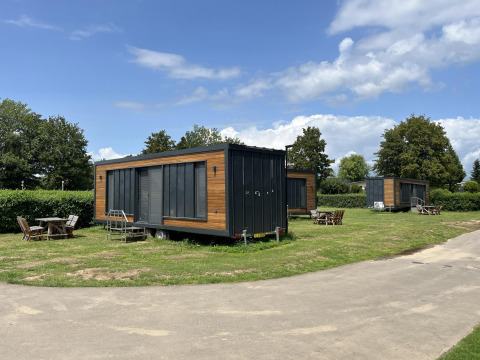 Tiny House-Lodges im Erholungspark und Yachthafen Rhederlaagse Meren, Niederlande, mit sonnigem Himmel.