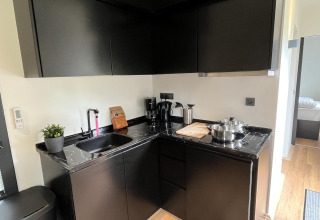 Moderne kleine zwarte keuken met marmeren werkblad in een Tiny House aan Rhederlaagse Meren, Nederland.