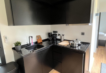 Moderne lille køkken med sorte skabe og marmorbord, placeret i Tiny House ved Rhederlaagse Meren, Holland.
