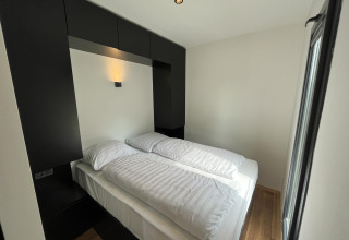 Moderne lille soveværelseslodge med dobbeltseng og strømlinet sort og hvid indretning i Holland.