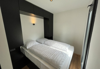 Camera moderna in una tiny house con letto matrimoniale e arredi nero e bianco nei Paesi Bassi.