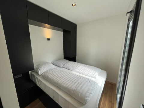 Dormitorio moderno y compacto con cama doble y decoración elegante en blanco y negro en los Países Bajos.