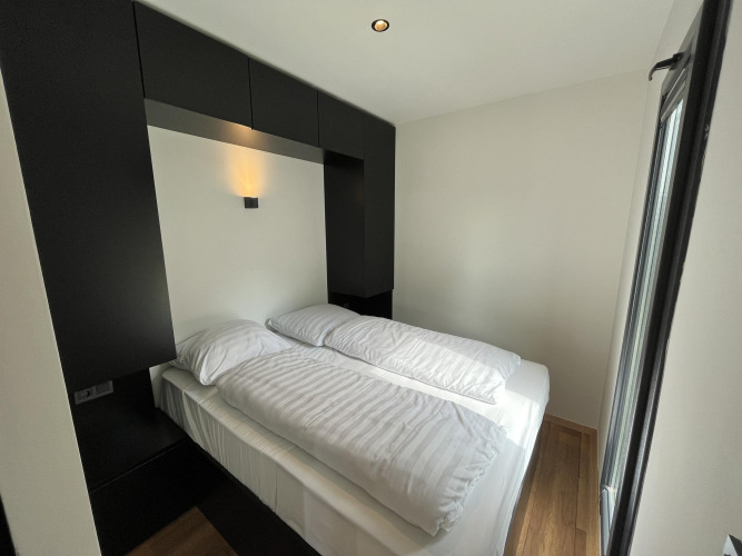 Moderne tiny house slaapkamer met tweepersoonsbed en zwart-witte inrichting in Nederland.