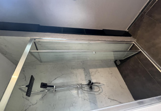 Moderne douchecabine met glazen schuifdeur en marmeren wanden in Tiny House bij Rhederlaagse Meren, Nederland.