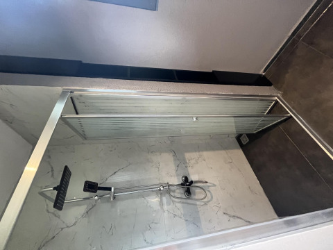 Moderne douchecabine met glazen schuifdeur en marmeren wanden in Tiny House bij Rhederlaagse Meren, Nederland.