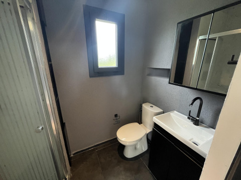 Baño moderno con inodoro, lavabo y ducha en una tiny house en el parque Rhederlaagse Meren, Países Bajos.