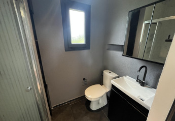 Baño moderno con inodoro, lavabo y ducha en una tiny house en el parque Rhederlaagse Meren, Países Bajos.