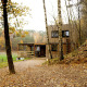 Moderne tiny house ved skovkant med træbeklædning, efterårsblade og terrasse, Shelter + jacuzzi.