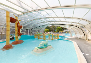Overdækket børnepool med legedyr og farverige skulpturer på Camping Le Bois de la Gachère, Pays de la Loire.