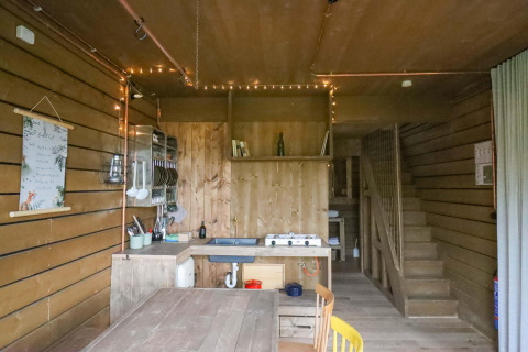 Cocina y comedor de madera en la tiny house Shelter + jacuzzi, Cosy Cabins, bosque de Limburg, Bélgica.