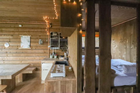 Interieur van Shelter + jacuzzi bij Cosy Cabins, houten tiny house met keuken en bed in het Limburgse bos.