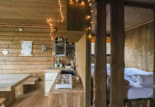 Binnenzicht Shelter + jacuzzi, een gezellig houten huisje met keuken en bed in het Limburgse woud.